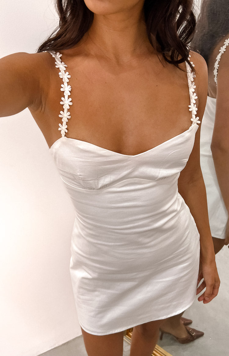 Close-up of the white mini dress showing the sweetheart neckline and delicate daisy chain shoulder straps