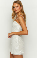 Side view of a white sequin mini dress with thin spaghetti straps and a fitted bodice showing the side zipper
