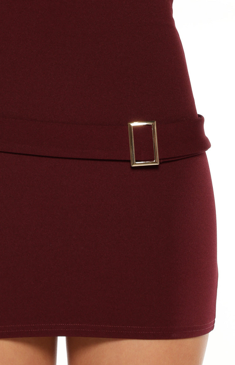 Close-up of the gold rectangular buckle detail on the waist of the burgundy micro mini dress