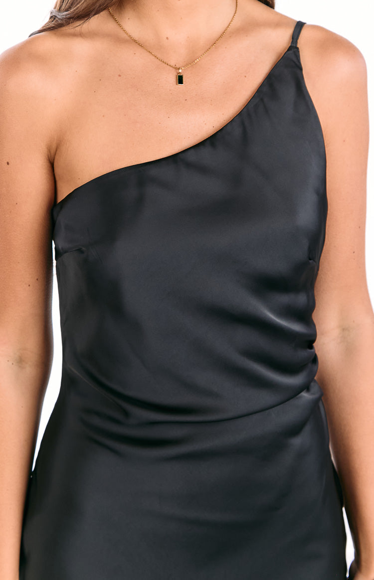 Close-up of the black satin one-shoulder maxi dress bodice showing the thin strap and fabric drape