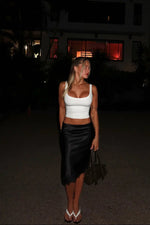 Black satin midi skirt with a subtle lace trim at the hem, highlighting its elegant sheen and fitted silhouette