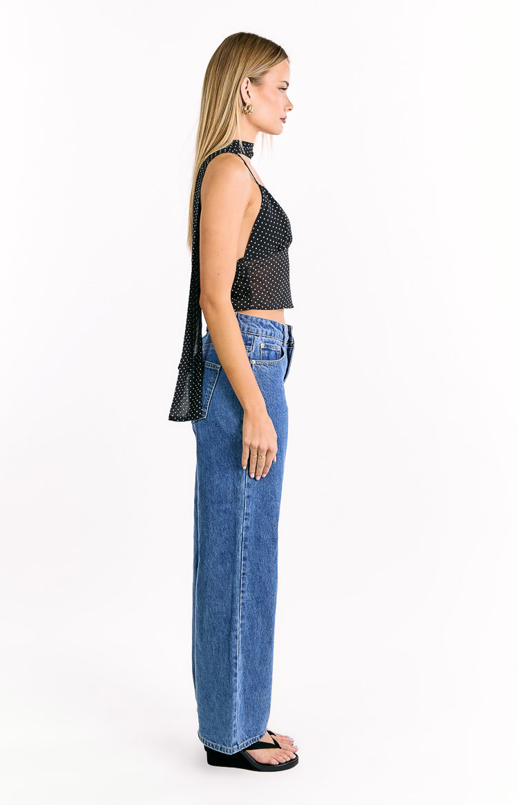 Side view of a black polka dot crop top with thin spaghetti straps and a long tie detail