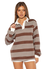 Close-up of the brown and white striped polo with a white collar, three-button placket, and long cuffed sleeves