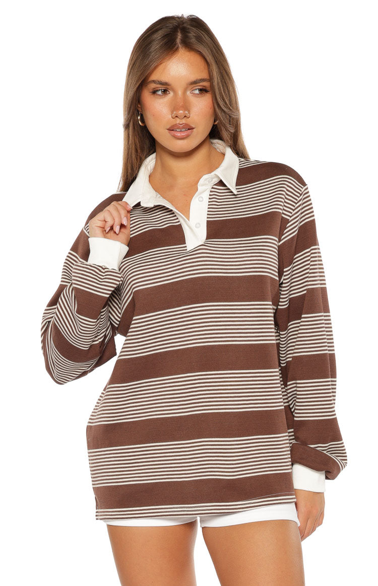 Close-up of the brown and white striped polo with a white collar, three-button placket, and long cuffed sleeves