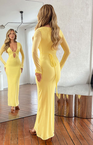 Rear view showing the tie-back detail at the waist of a yellow long sleeve maxi dress