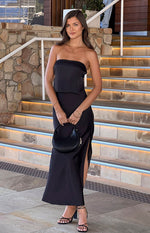 Full length view of a black satin maxi skirt with a high left side slit