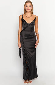 Front view of a black satin maxi dress with a ruffled V-neckline, thin straps, and a diagonal ruffle slit