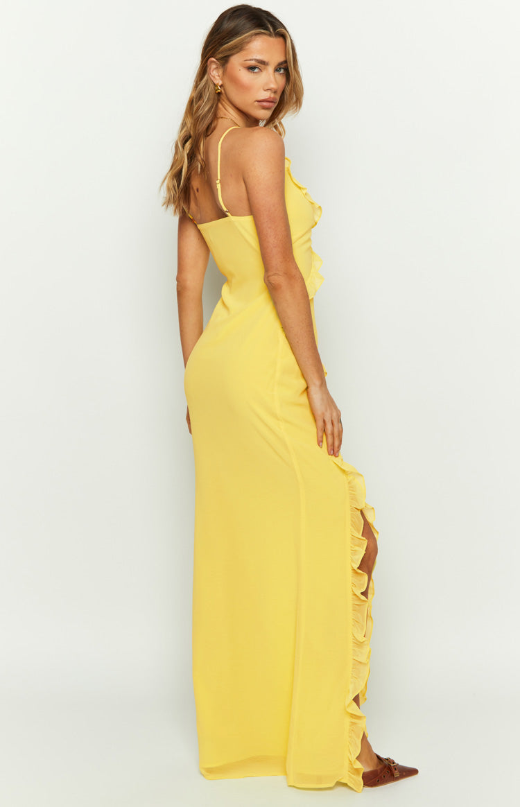 Side view of a yellow maxi dress with ruffles along the side slit and thin spaghetti straps