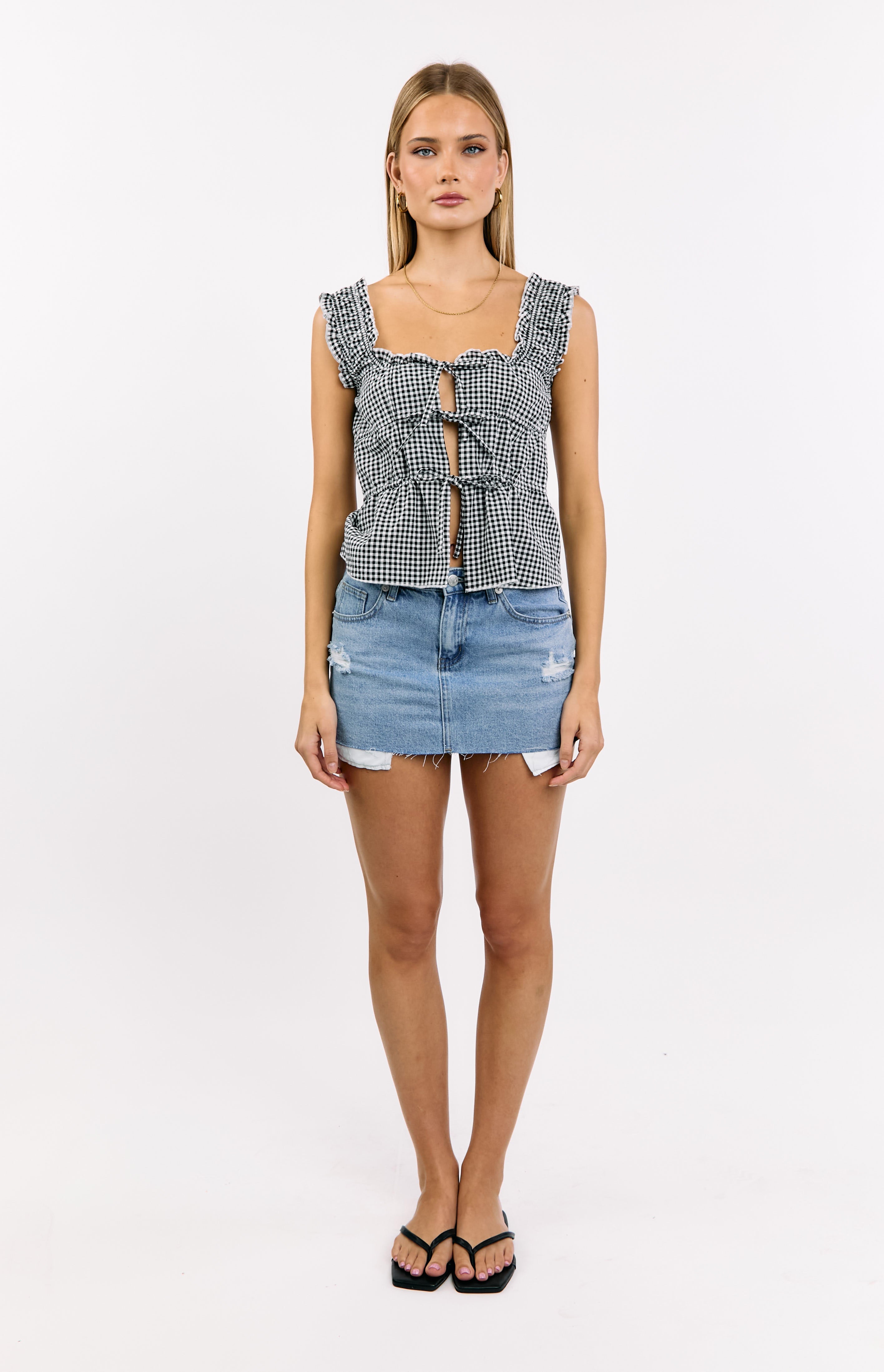 Front view of a black gingham tie top with a square neckline, ruffled shoulder straps, and multiple ties down the front