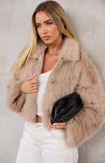 Close-up of the light brown faux fur jacket showing the shaggy texture and open front with zipper