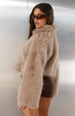 Side view of a light brown cropped faux fur jacket with long fluffy sleeves