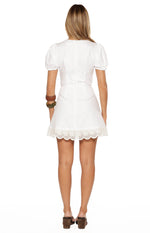 Rear view of the white mini dress with short puff sleeves and broderie trim on the hem