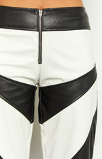 Close-up of the front zipper closure on white PU pants with a black waistband and diagonal black panels