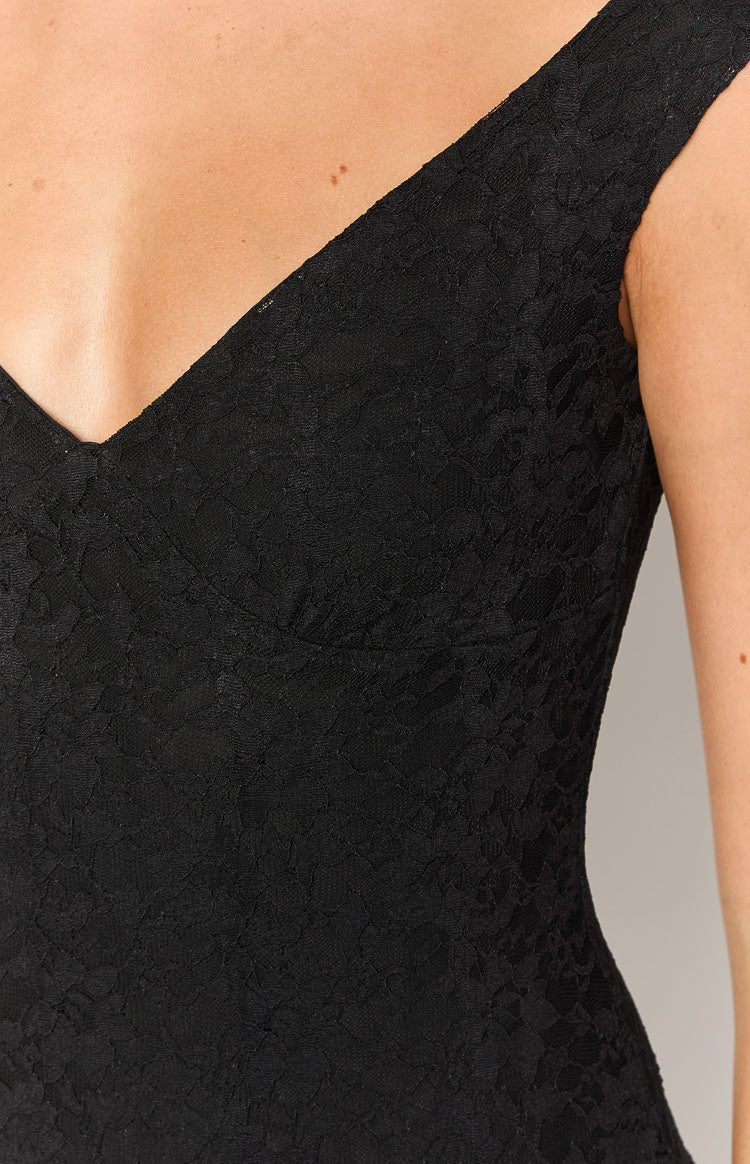 Close-up of the off-shoulder V-neckline and textured black floral lace of a fitted mini dress