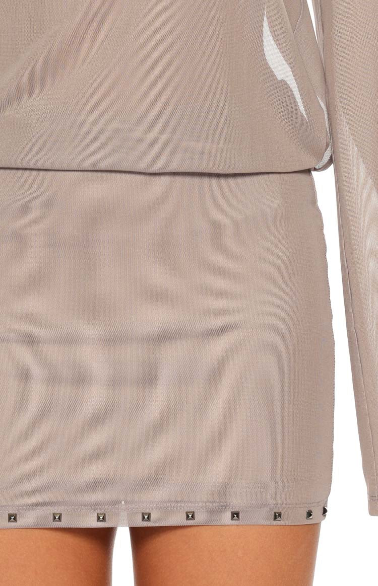 Close-up of the brown sheer mesh mini dress showing the pyramid stud detail along the hem