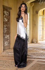 Side view of the black satin straight leg pants, highlighting the smooth fabric and relaxed, flowy fit