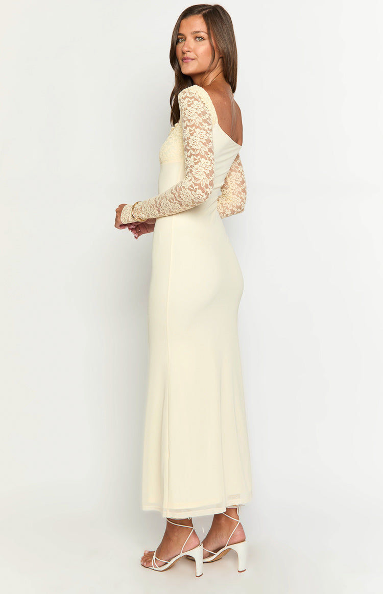 Side view of a cream maxi dress showing the fitted silhouette, long floral lace sleeves, and sheer hem