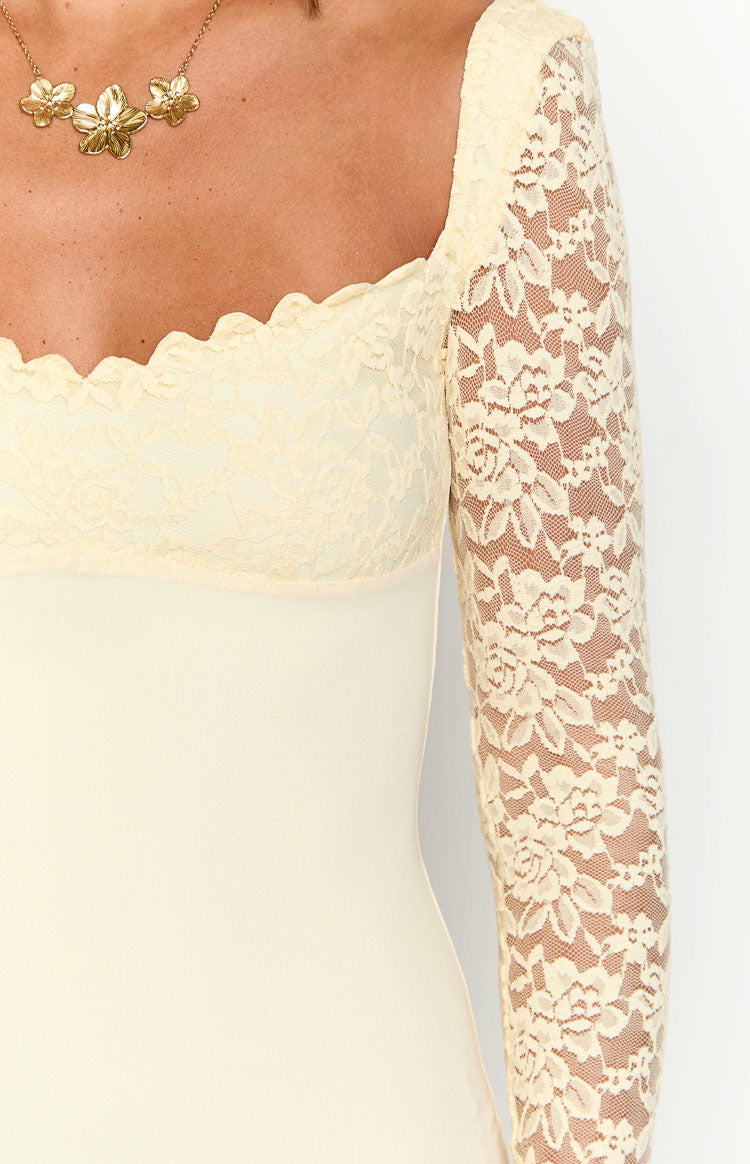 Close-up of the cream maxi dress showing the scalloped lace sweetheart neckline and sheer floral lace long sleeve