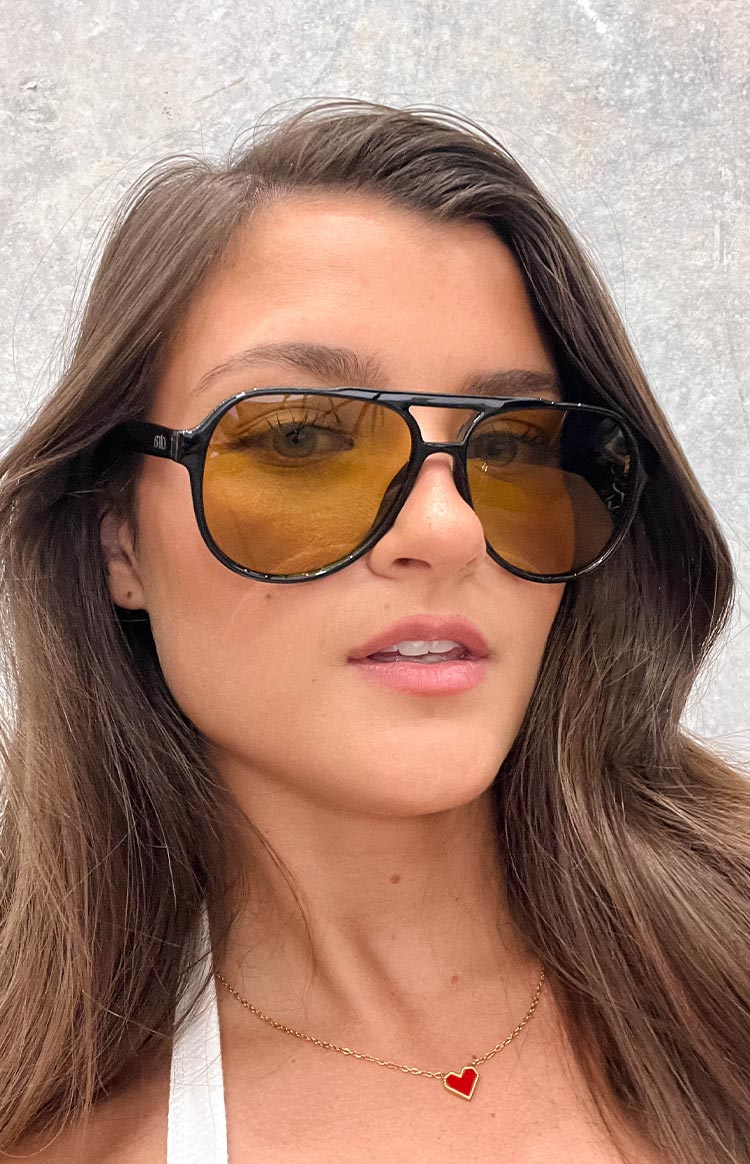 Close-up of black aviator sunglasses with yellow-orange tinted lenses and a double bridge design