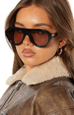 Close-up of black aviator sunglasses with thick frames and brown tinted lenses
