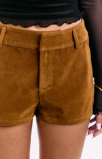 Detail shot of the tan suedette shorts showing the flat front waistband, belt loops, and concealed fly