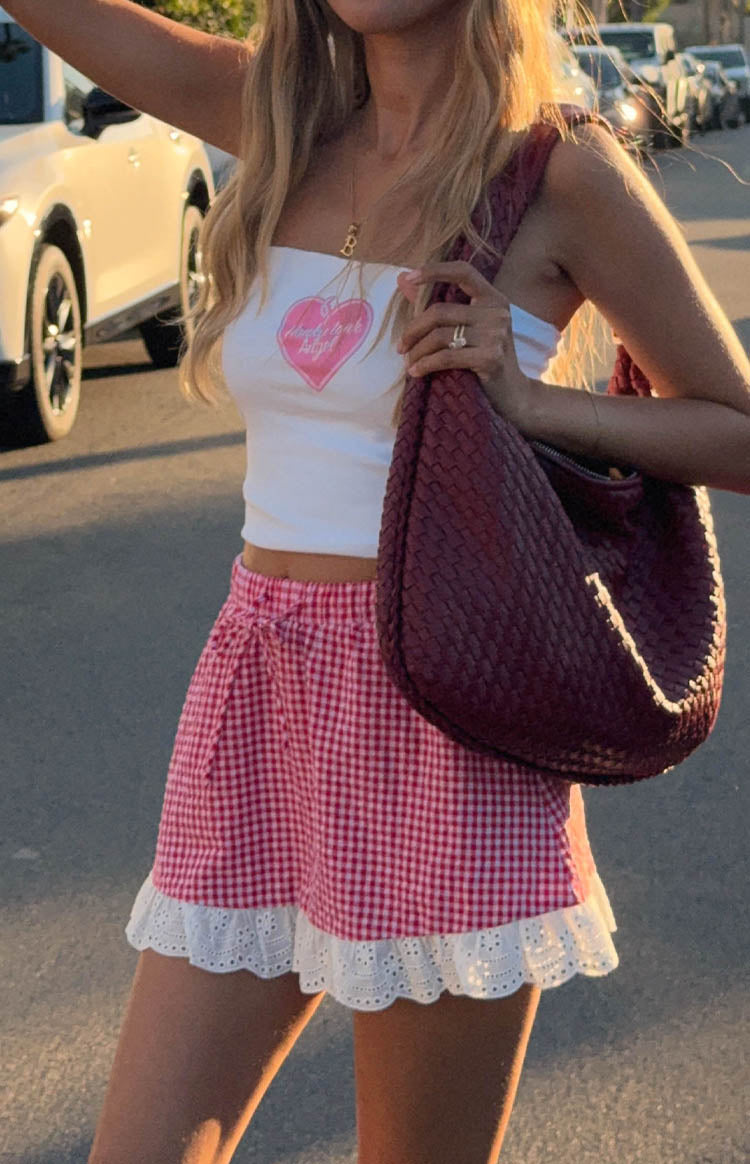 Close-up of the red gingham mini skirt showing the white eyelet lace trim and drawstring waist