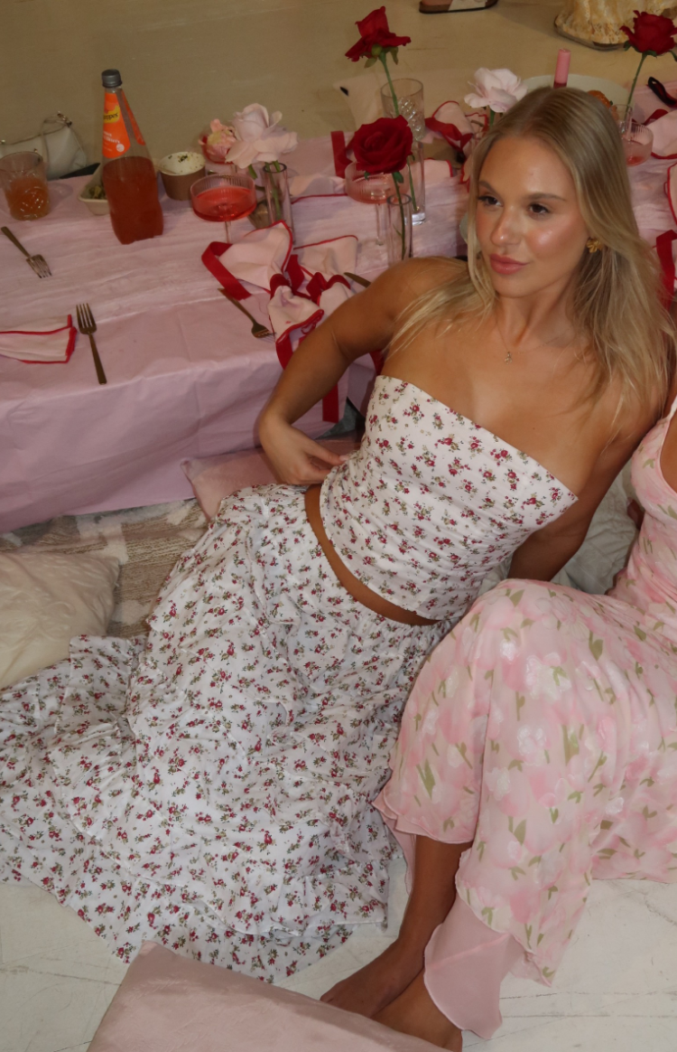 Flowy white floral maxi skirt with tiered ruffles, seen from a seated position