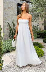 White satin maxi dress with a straight neckline, delicate lace trim, thin spaghetti straps, and empire waist