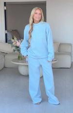 Front view of light blue mid-rise slouch fit trackpants with wide, relaxed legs