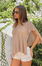 Side view of a light brown metallic knit poncho with an off-shoulder neckline and wide open sleeve