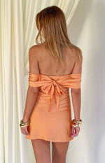 Rear view of an orange satin off-shoulder mini dress featuring a large tie-back bow