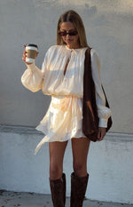 Front view of a pearl satin mini dress with tie neck, blouson top, voluminous long sleeves, and tiered skirt