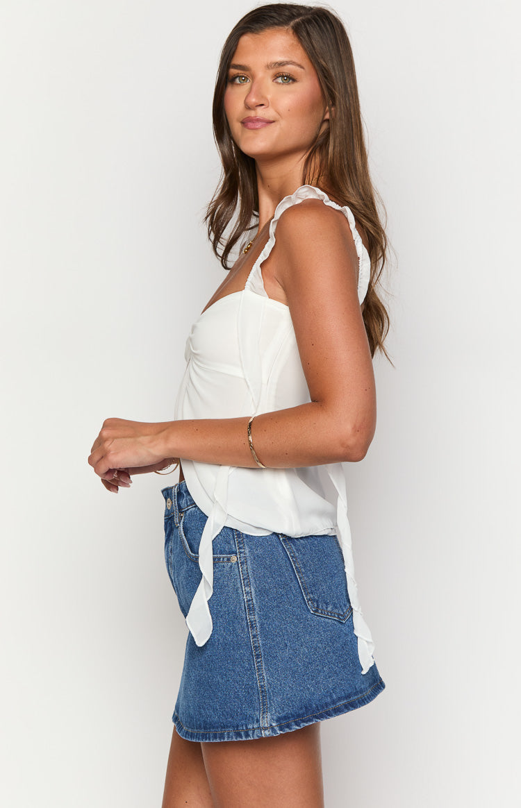Side view of a mid wash denim mini skirt with an A-line shape and visible side seams