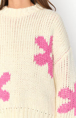 Close-up of the cream chunky knit sweater with pink flower patterns on the shoulder and sleeve