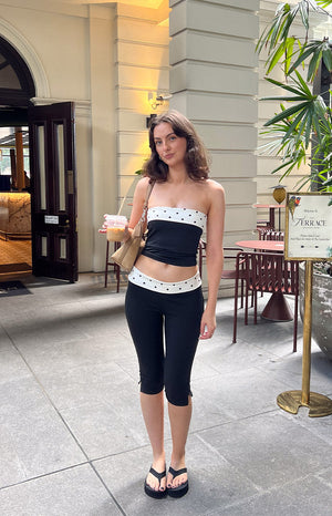 Black capris with a white polka dot band at the waist and small side slits on the cropped leg hem
