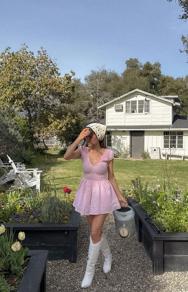 Pink gingham playsuit with smocked V-neck bodice, short ruffled sleeves, and a flared shorts hem