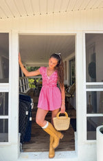 Full view of a red gingham playsuit with a V-neck, white lace trim, puff sleeves, and a shirred waist