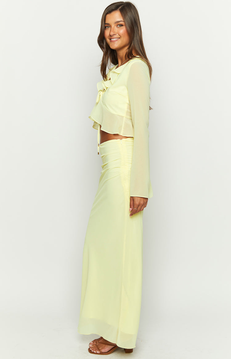 Side view of a yellow maxi skirt with ruched hip detail and a flowy, sheer overlay