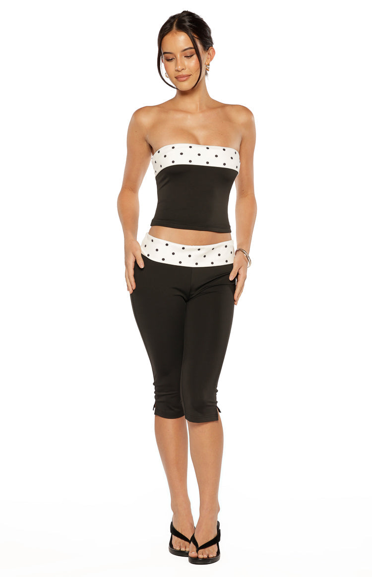 Front view of a black strapless top featuring a wide white band with black polka dots at the bust