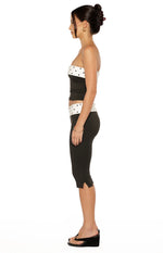 Front view of a black strapless top with white polka dot bands at the straight neckline and cropped hem