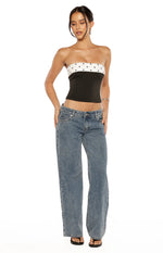 Side view of a black strapless top with white polka dot bands at the bust and hem