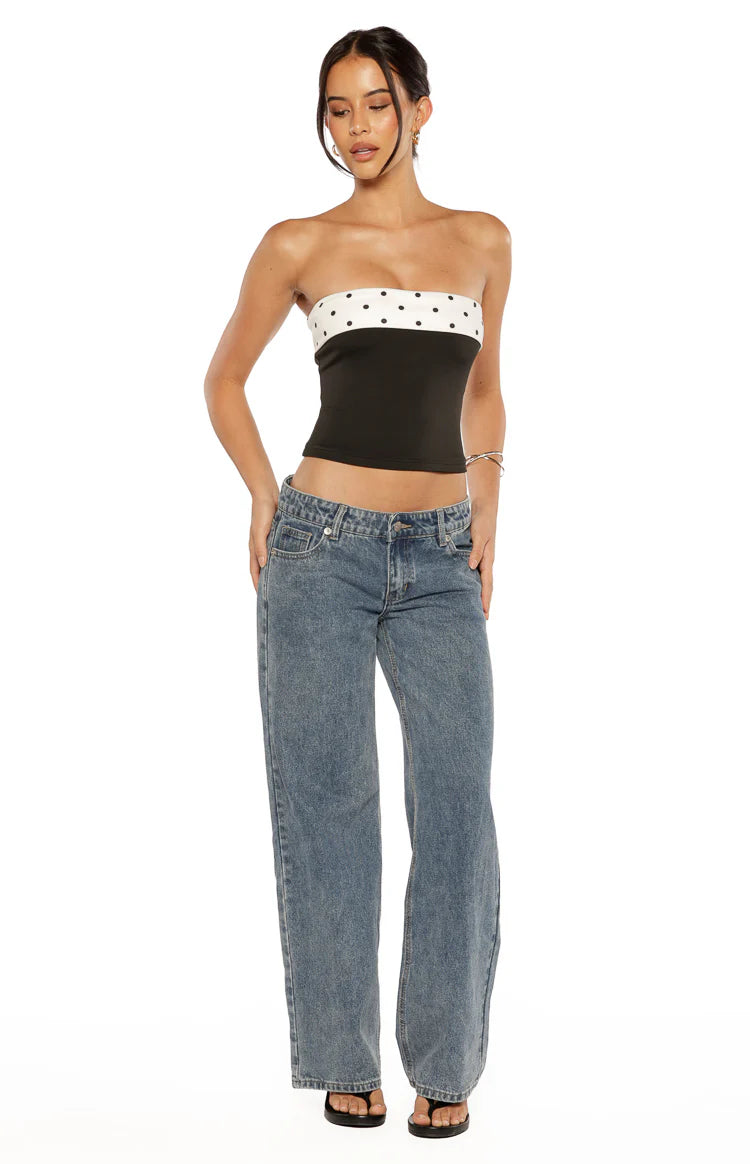 Side view of a black strapless top with white polka dot bands at the bust and hem
