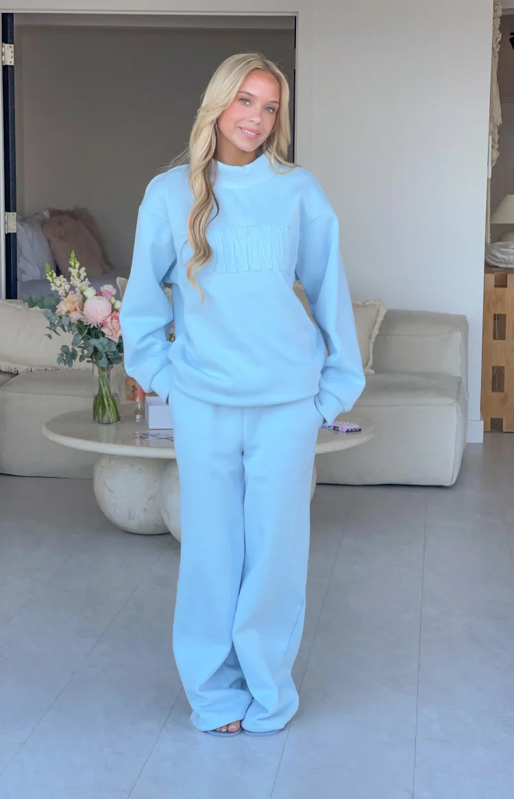Light blue mock neck sweater with long sleeves, relaxed fit, and 'BEGINNING' applique text