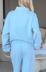 Back view of a light blue mock neck sweater with dropped shoulders and matching relaxed fit track pants