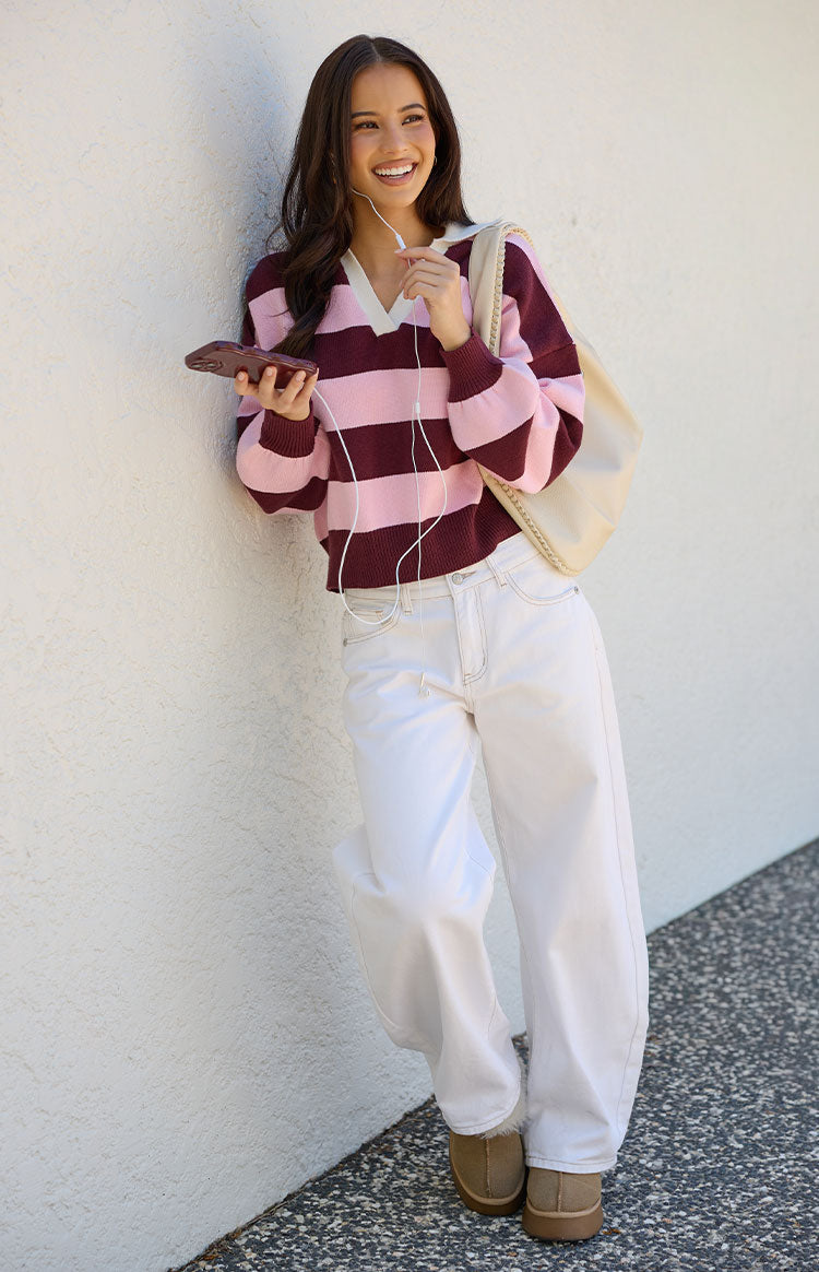 Relaxed fit pink and burgundy striped polo sweater with a cream V-neck collar and long sleeves