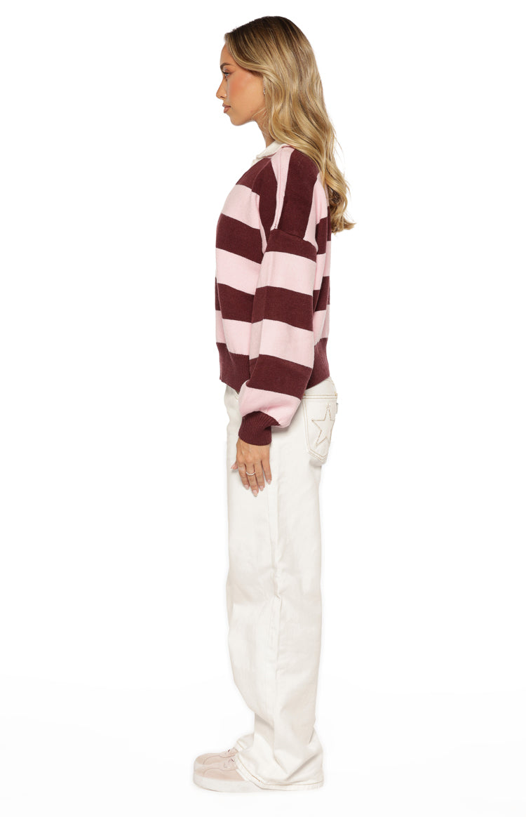 Side view of a pink and maroon striped long sleeve polo with a relaxed fit and ribbed cuffs