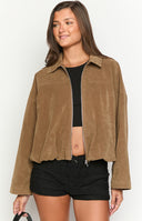 Close-up of a model wearing an open brown suede-like or corduroy jacket over a black ribbed top