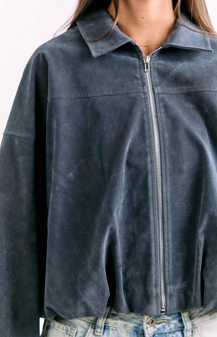 Close-up of the steel grey suedette bomber jacket featuring a silver full-zip front, pointed collar, and chest seam