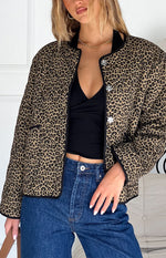 Close-up of the leopard print quilted jacket with black band collar, piping, and silver floral buttons
