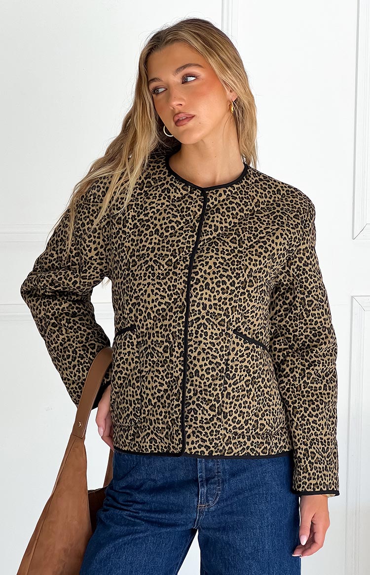 Front view of a leopard print quilted jacket with black piping detail and a round neckline
